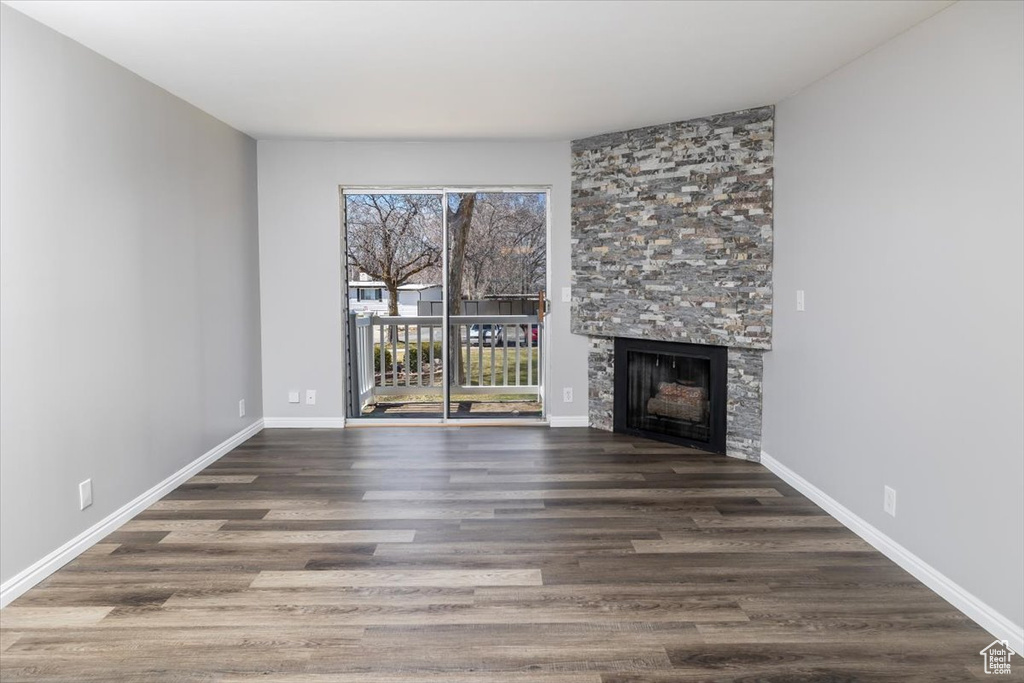 Unfurnished living room featuring plenty of natural light, a stone fireplace, and dark hardwood / wood-style floors