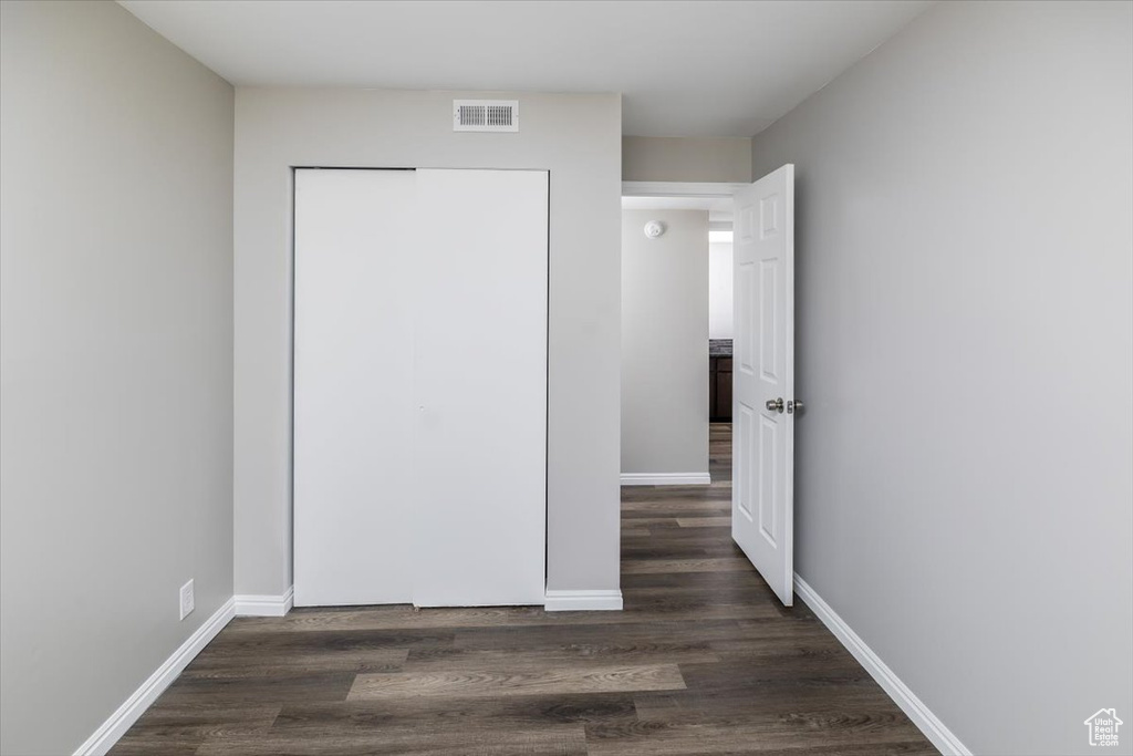 Unfurnished bedroom with dark hardwood / wood-style floors and a closet