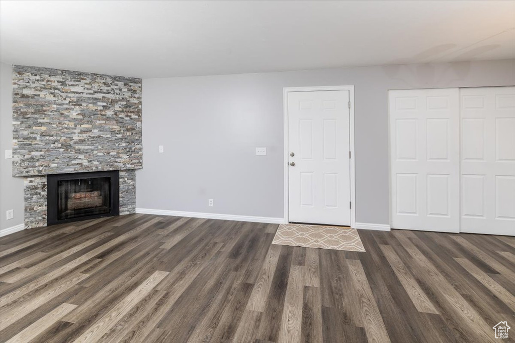 Unfurnished living room featuring dark hardwood / wood-style flooring and a stone fireplace
