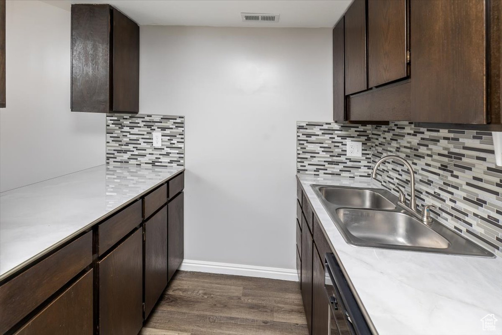 Kitchen featuring backsplash, dark brown cabinetry, sink, and dark hardwood / wood-style floors