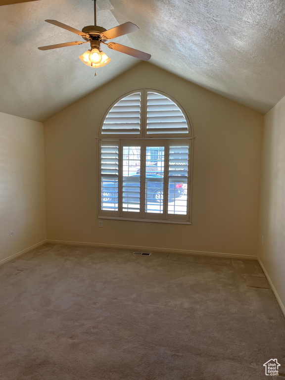 Carpeted spare room with ceiling fan, a textured ceiling, and vaulted ceiling