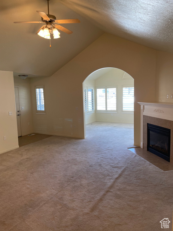 Unfurnished living room with light colored carpet, ceiling fan, a tile fireplace, and lofted ceiling