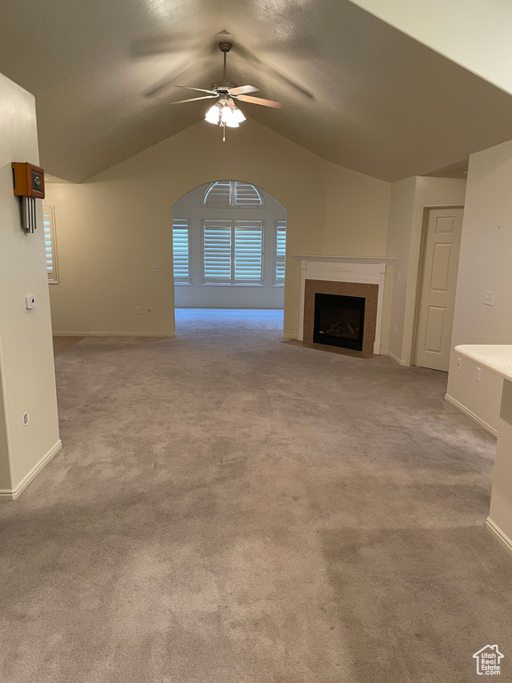Unfurnished living room featuring lofted ceiling, ceiling fan, and light colored carpet
