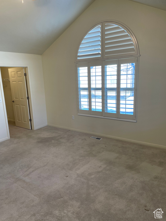 Unfurnished room featuring lofted ceiling and light colored carpet