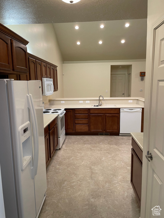 Kitchen featuring white appliances, kitchen peninsula, sink, and light tile floors
