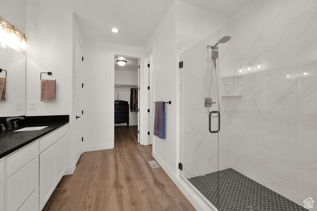 Bathroom with an enclosed shower, large vanity, and hardwood / wood-style floors