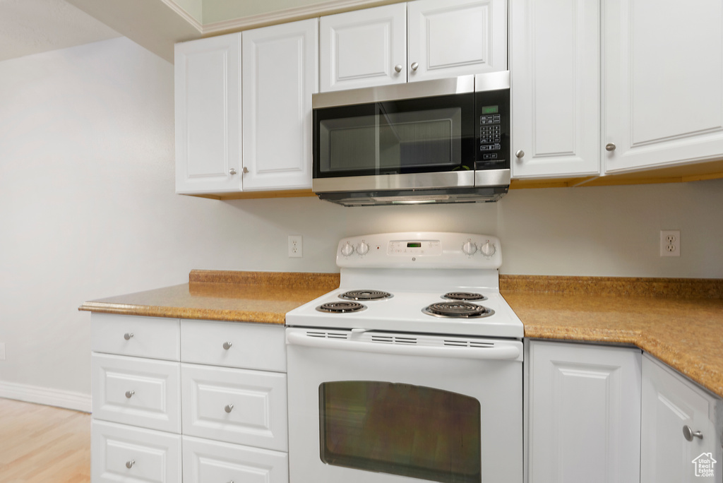 Kitchen featuring white range with electric stovetop, white cabinetry, and light hardwood / wood-style floors