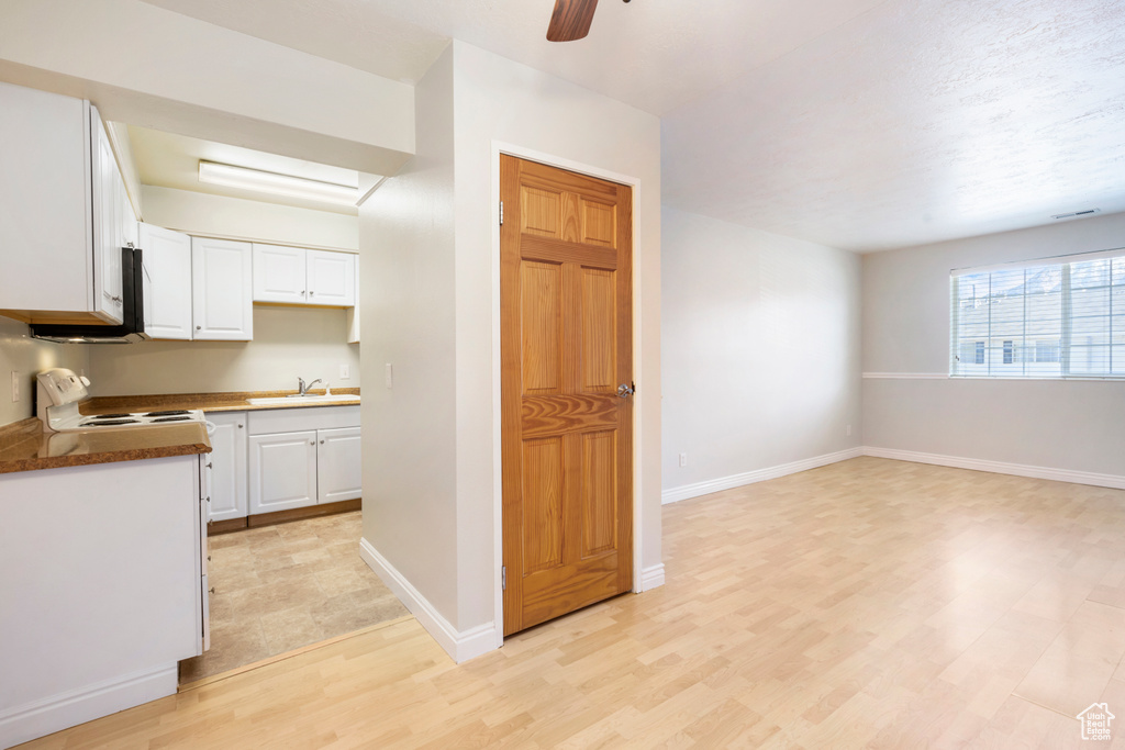 Kitchen featuring white cabinets, ceiling fan, range, and light hardwood / wood-style floors