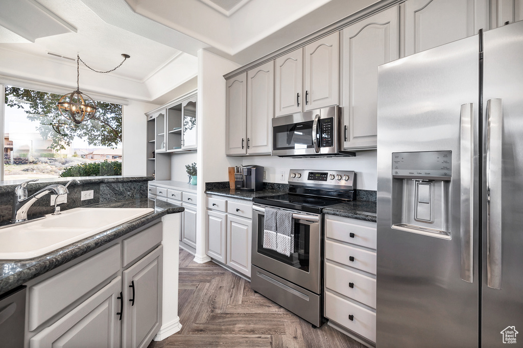 Kitchen featuring gray cabinets, dark parquet floors, sink, a notable chandelier, and appliances with stainless steel finishes
