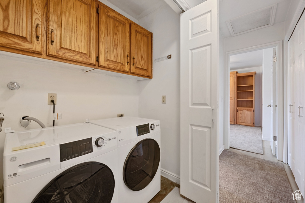 Laundry room with light colored carpet, cabinets, and washer and clothes dryer