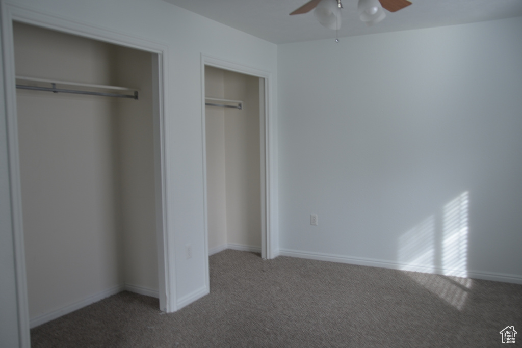 Unfurnished bedroom featuring dark carpet and ceiling fan