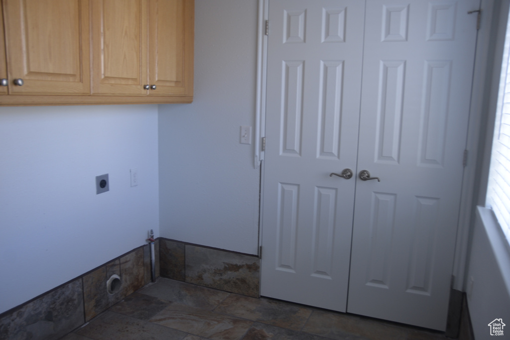 Laundry room featuring hookup for an electric dryer, cabinets, and dark tile floors