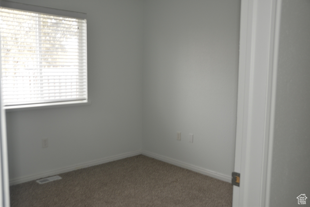 Spare room with dark colored carpet