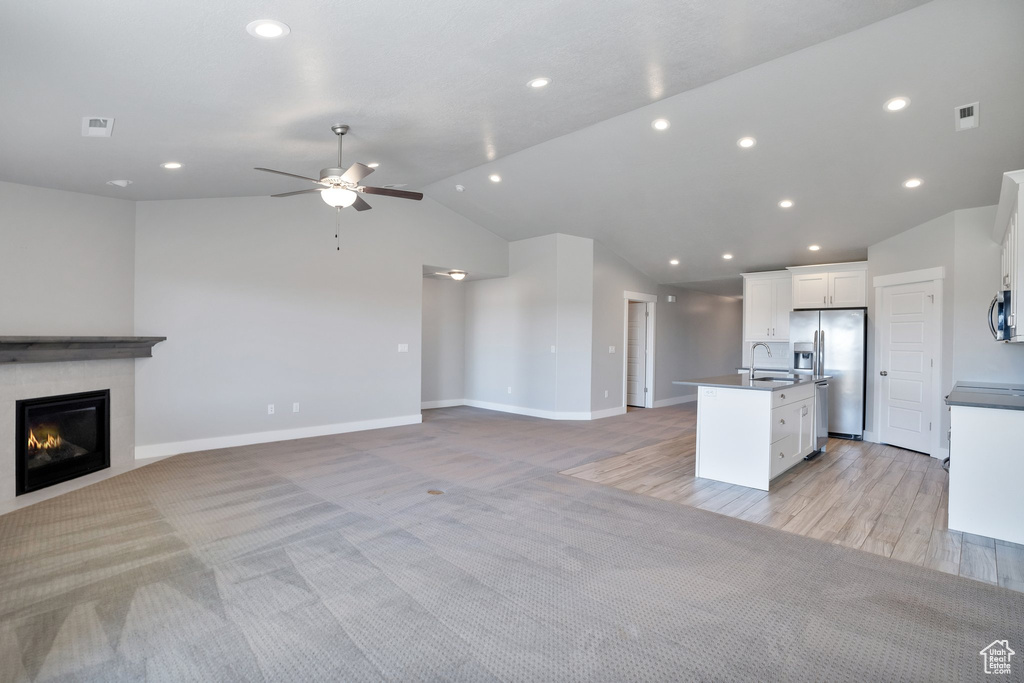 Kitchen featuring lofted ceiling, ceiling fan, light carpet, white cabinets, and stainless steel appliances