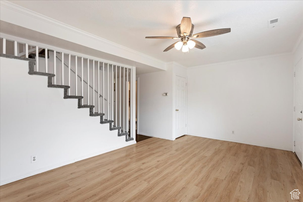 Empty room featuring light wood-type flooring, ceiling fan, and ornamental molding