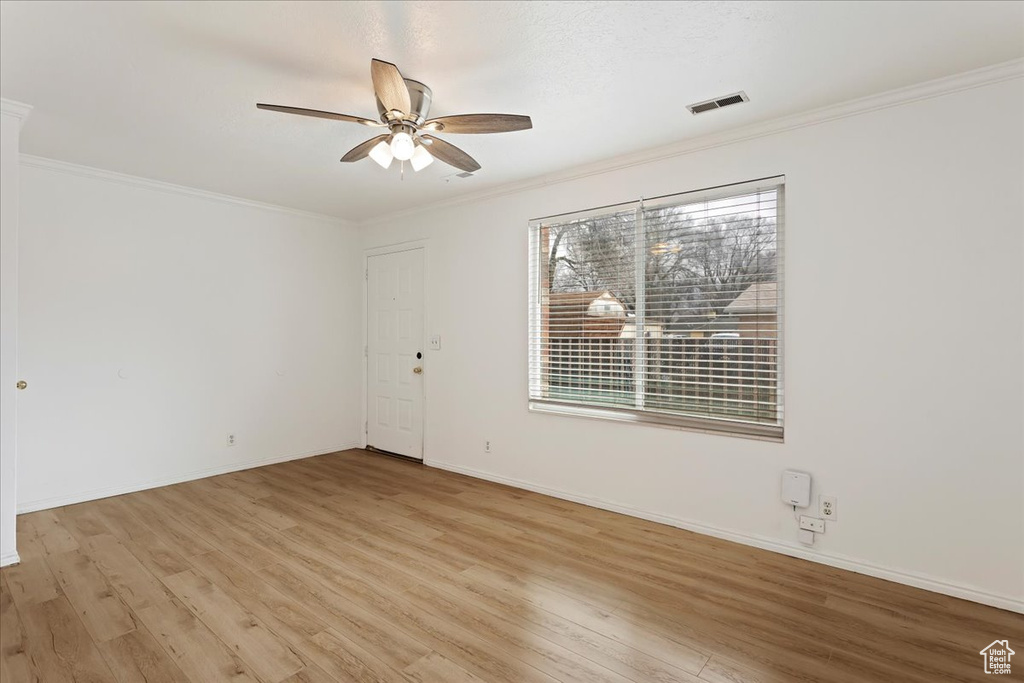 Unfurnished room with a healthy amount of sunlight, crown molding, ceiling fan, and light wood-type flooring