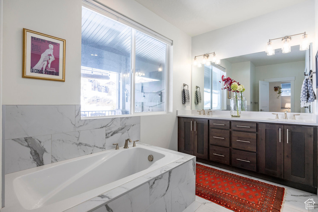 Bathroom with dual bowl vanity, tile floors, and tiled tub