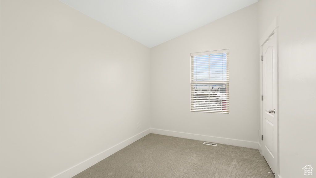 Unfurnished room with vaulted ceiling and light carpet