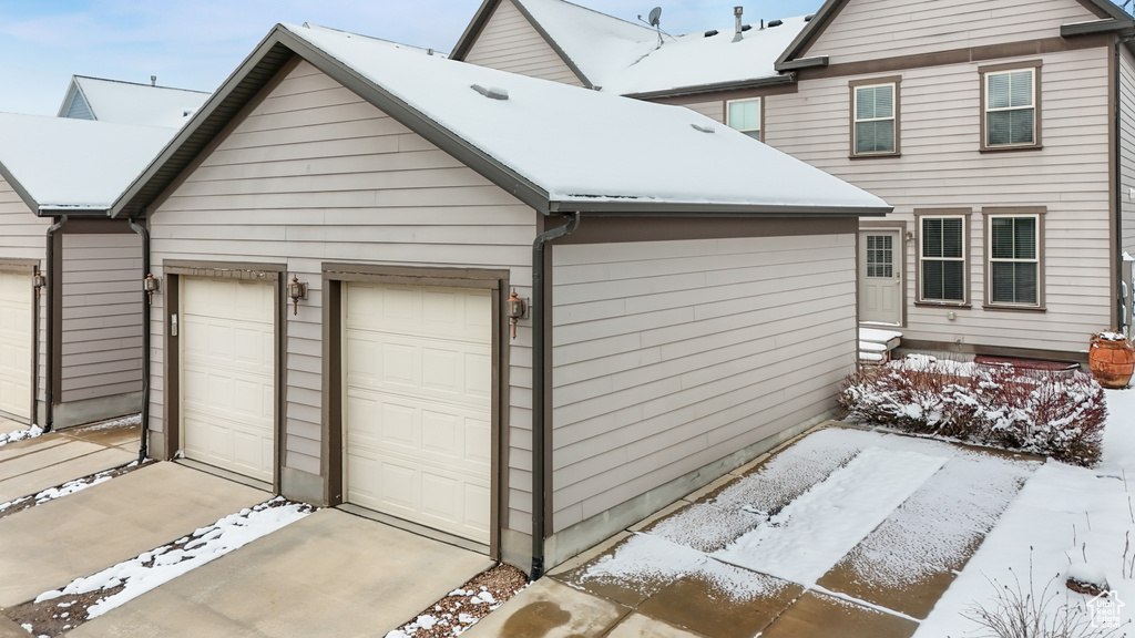 Snow covered garage featuring wooden walls