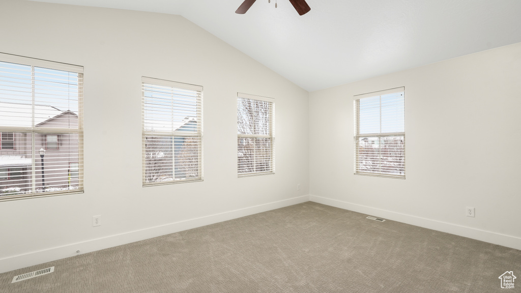 Unfurnished room with carpet flooring, a wealth of natural light, vaulted ceiling, and ceiling fan