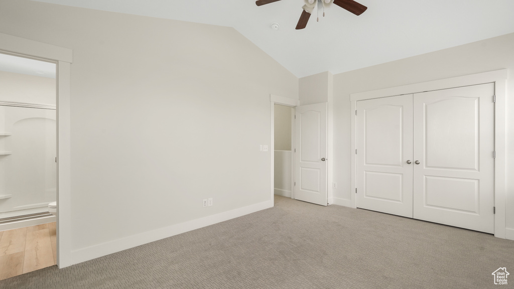 Unfurnished bedroom with connected bathroom, light carpet, lofted ceiling, a closet, and ceiling fan