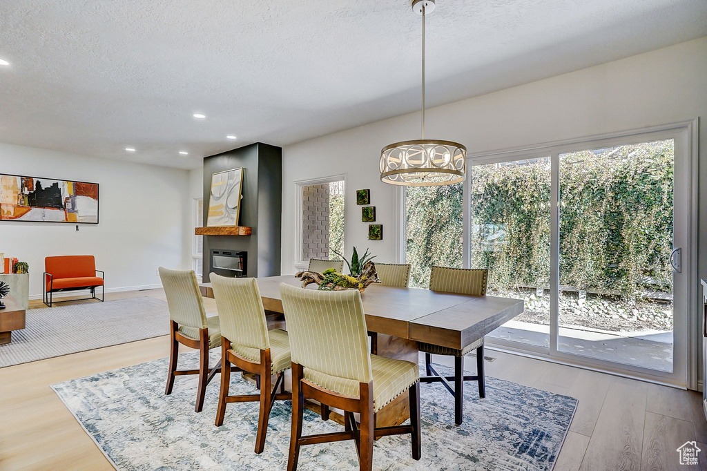Dining room with a notable chandelier, light hardwood / wood-style flooring, and a textured ceiling