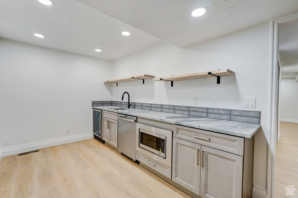 Kitchen featuring sink, light hardwood / wood-style flooring, stainless steel appliances, and light stone countertops