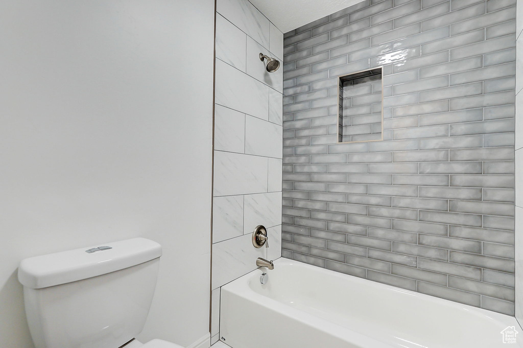 Bathroom with toilet and tiled shower / bath combo