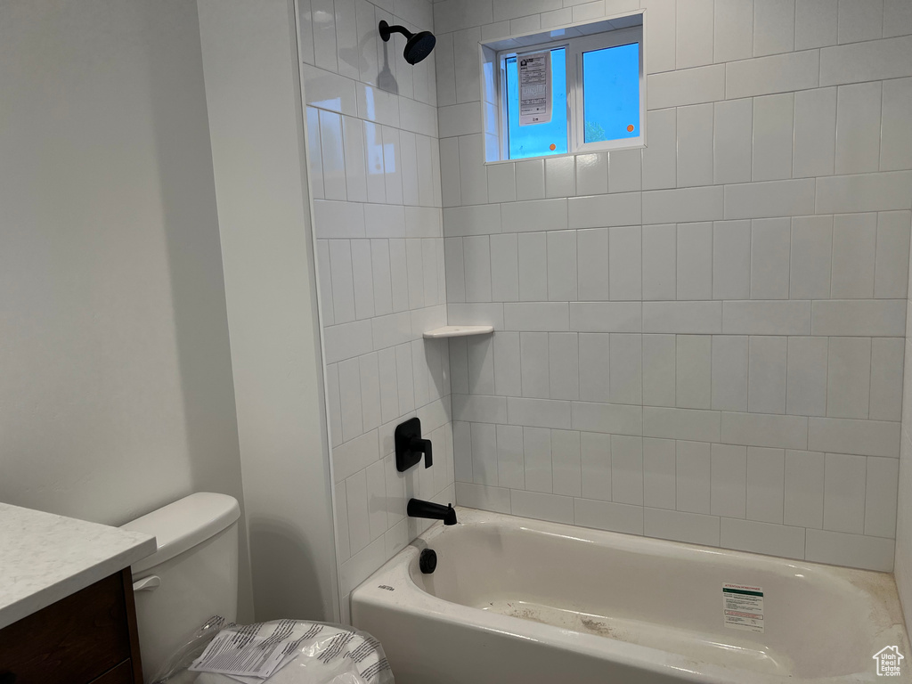 Full bathroom featuring tiled shower / bath combo, vanity, and toilet