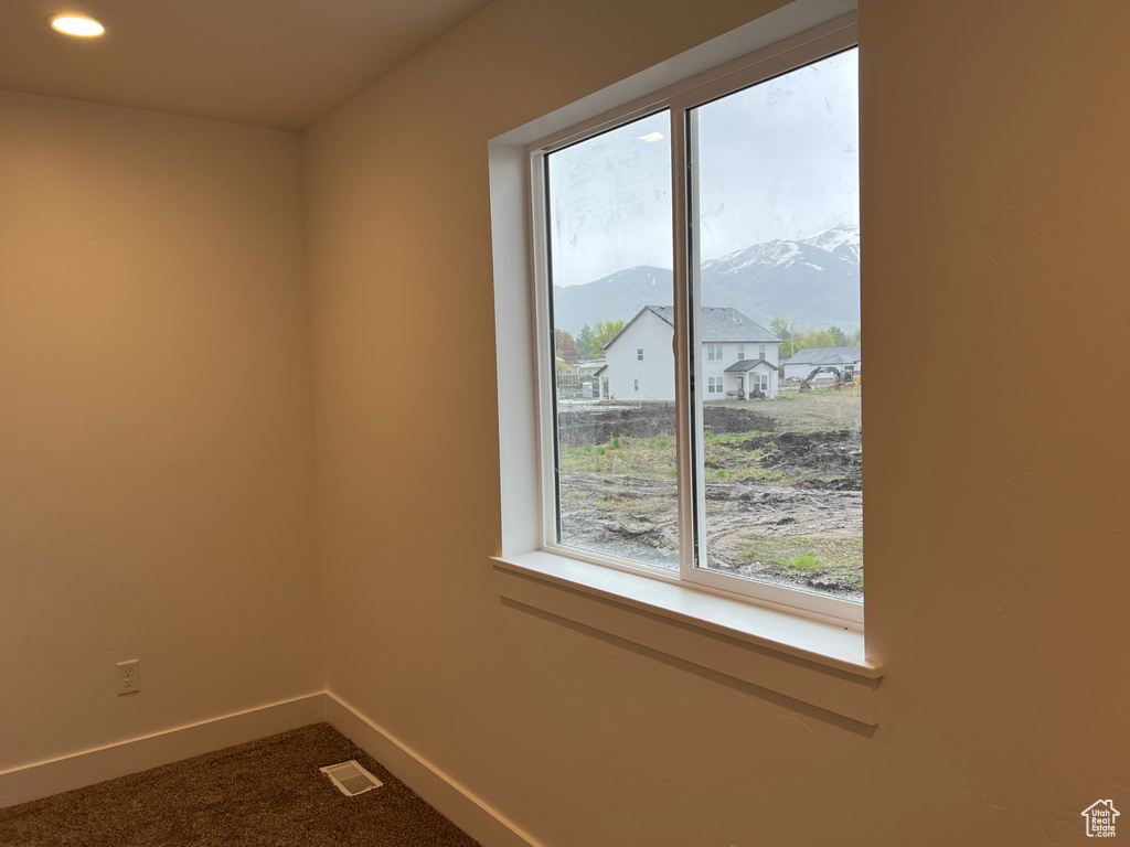 Unfurnished room with carpet, a mountain view, and a healthy amount of sunlight