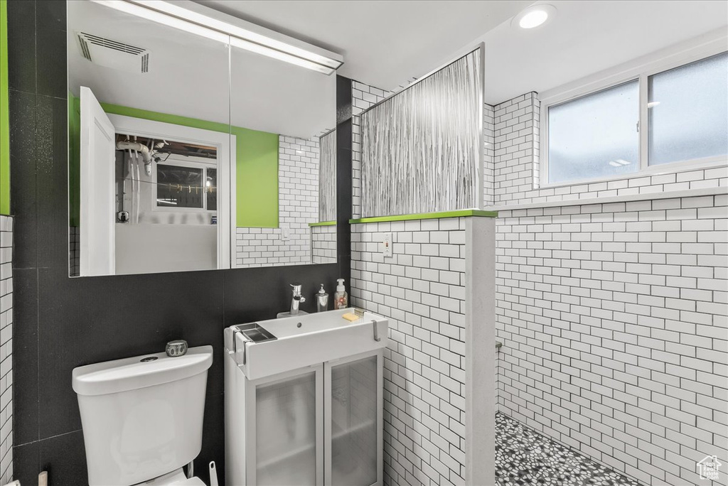 Bathroom featuring toilet, tile walls, and tiled shower