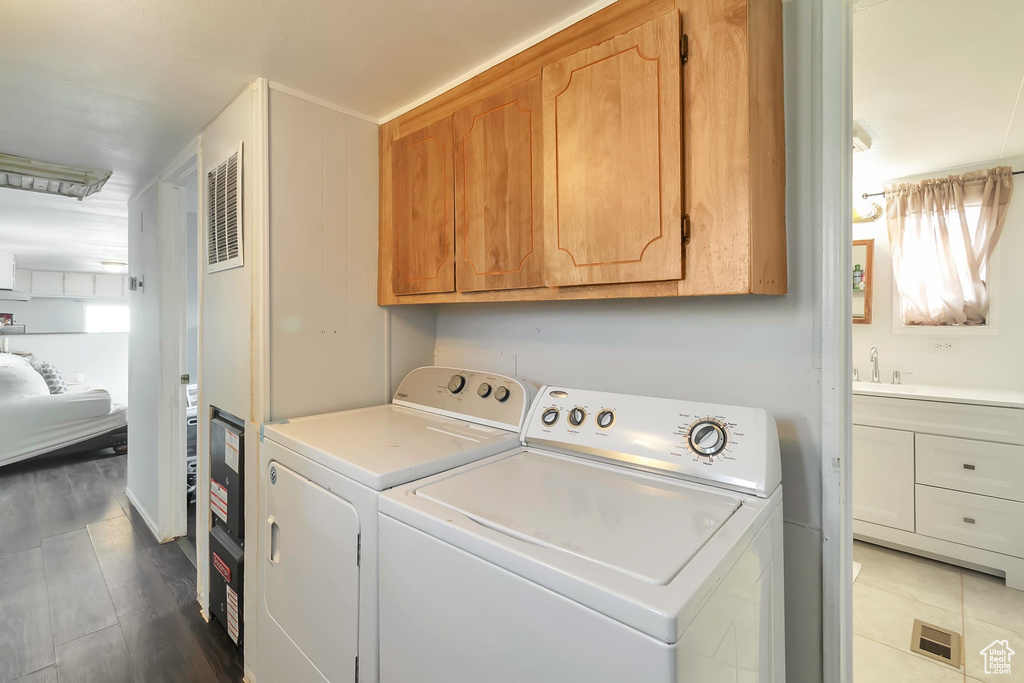 Clothes washing area featuring cabinets, hardwood / wood-style flooring, and washing machine and clothes dryer