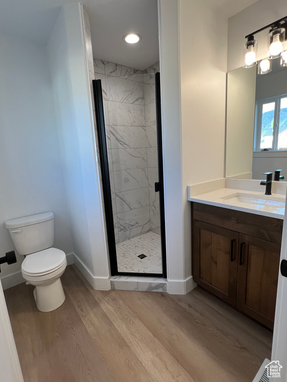 Bathroom featuring walk in shower, vanity, toilet, and hardwood / wood-style flooring