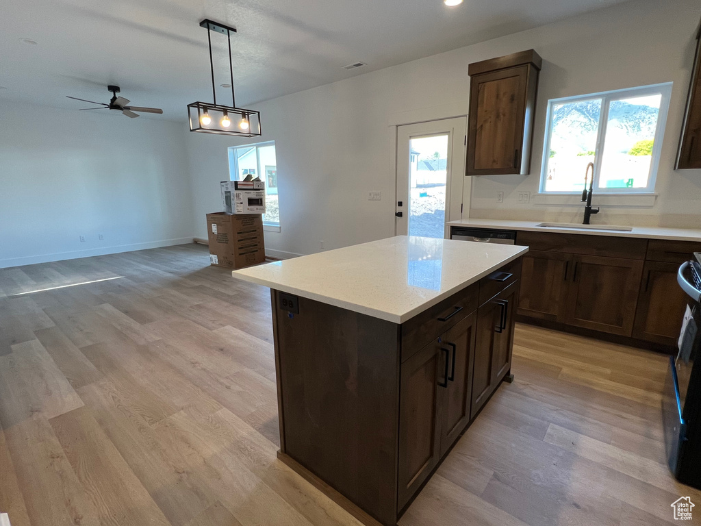 Kitchen with hanging light fixtures, ceiling fan, light hardwood / wood-style floors, sink, and a center island