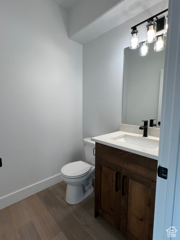 Bathroom featuring hardwood / wood-style floors, vanity, an inviting chandelier, and toilet
