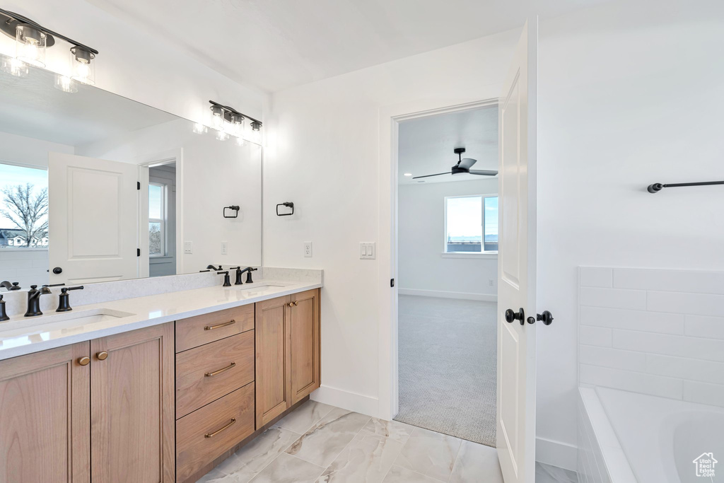 Bathroom featuring a bathtub, ceiling fan, double sink vanity, and tile floors