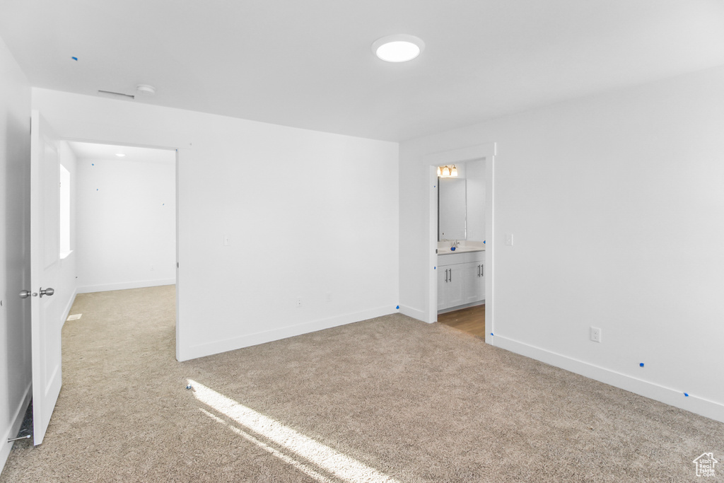Unfurnished bedroom with connected bathroom and light colored carpet