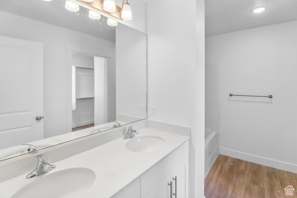 Bathroom featuring wood-type flooring, dual bowl vanity, and shower / washtub combination