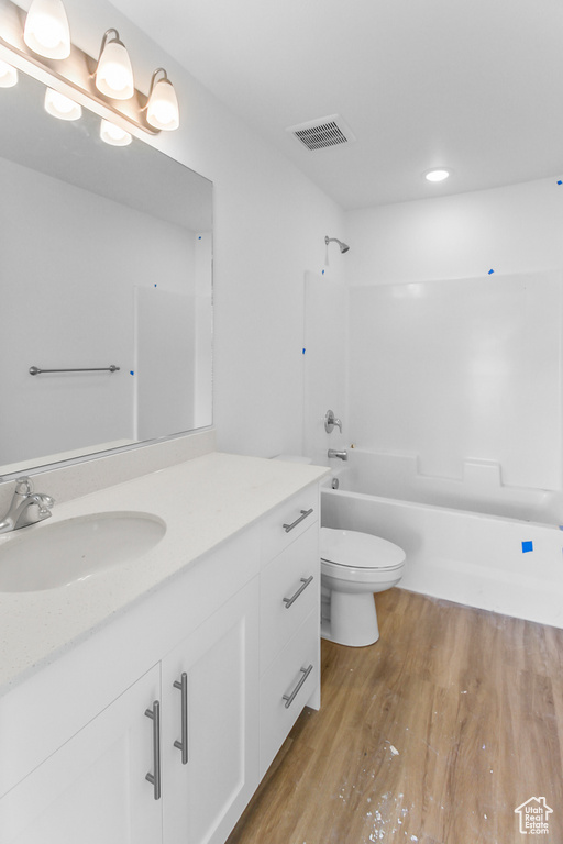 Full bathroom featuring toilet, oversized vanity, bathing tub / shower combination, and hardwood / wood-style floors