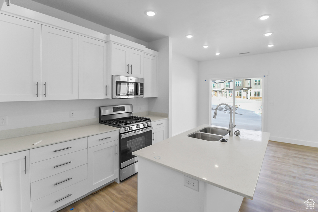 Kitchen featuring white cabinets, light wood-type flooring, and stainless steel appliances