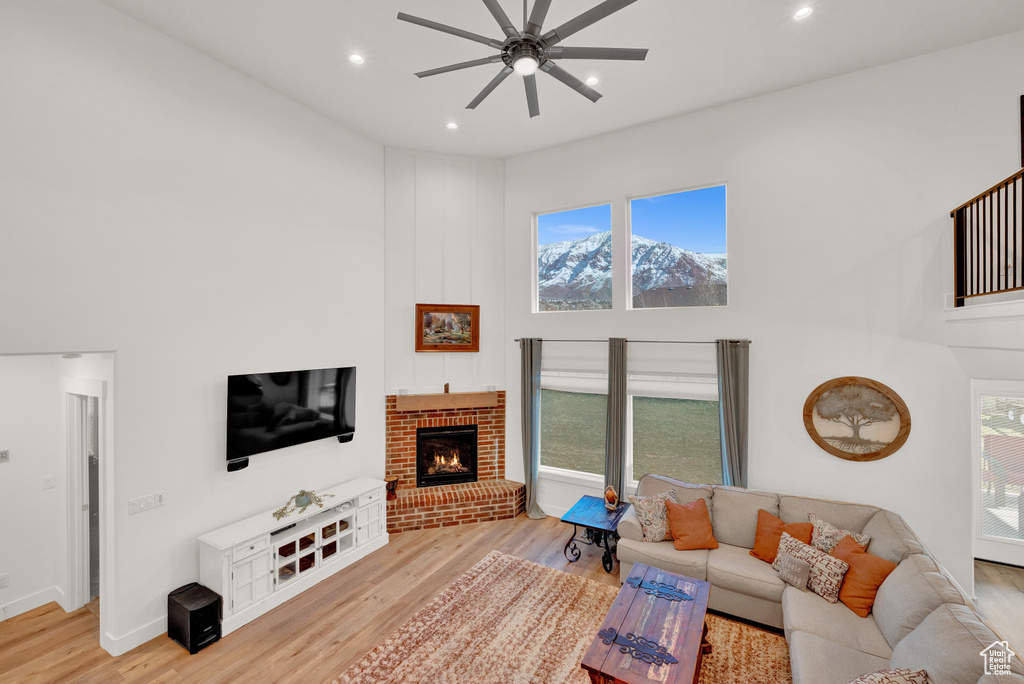 Living room featuring a wealth of natural light, ceiling fan, a brick fireplace, and light hardwood / wood-style floors