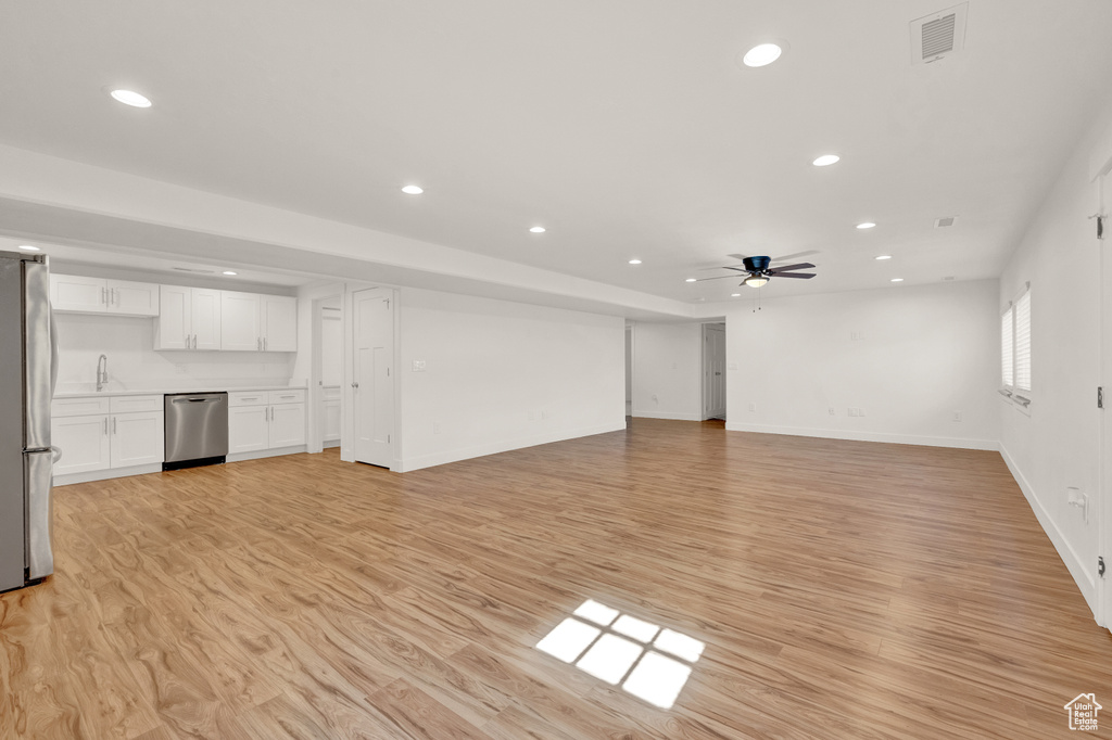 Unfurnished living room featuring sink, ceiling fan, and light hardwood / wood-style floors