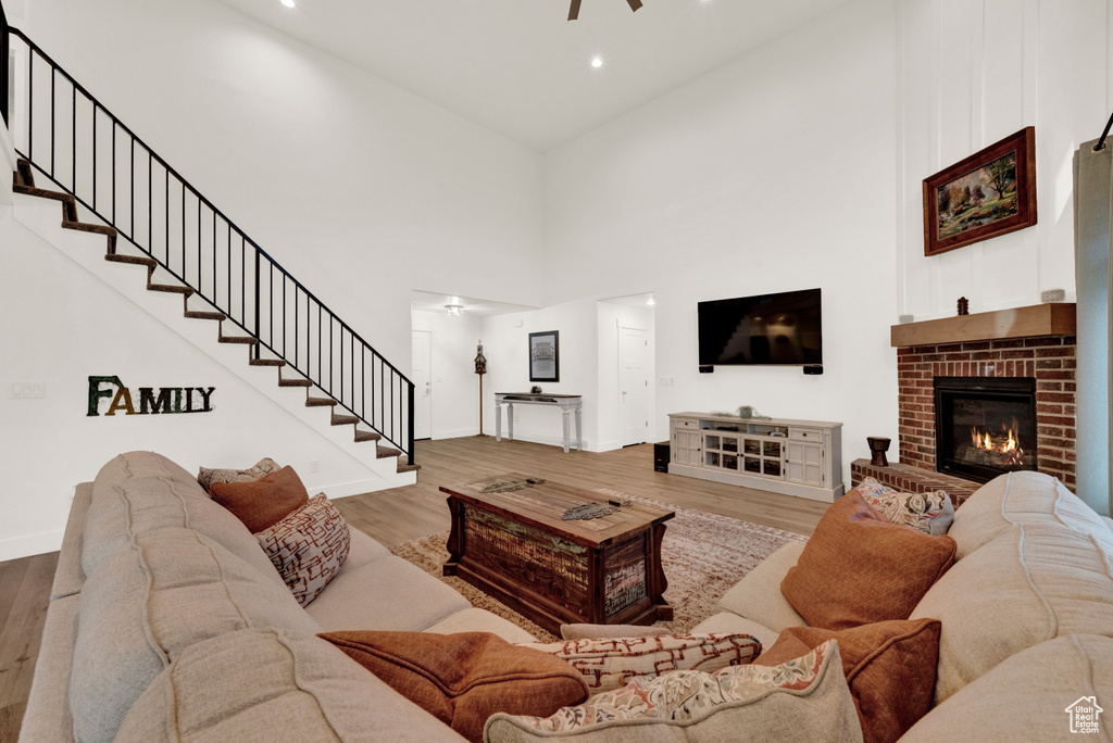 Living room with a fireplace, high vaulted ceiling, and wood-type flooring