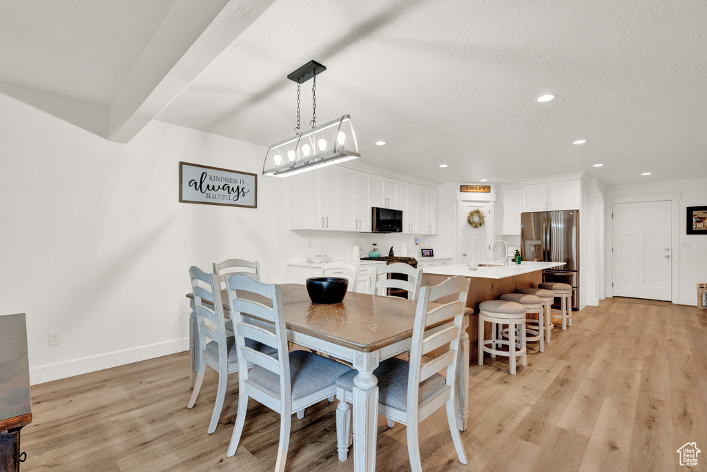 Dining space featuring sink, light hardwood / wood-style flooring, and a notable chandelier