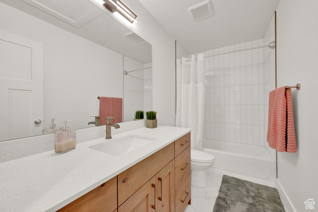 Full bathroom featuring vanity with extensive cabinet space, tile floors, shower / bath combination with curtain, and toilet