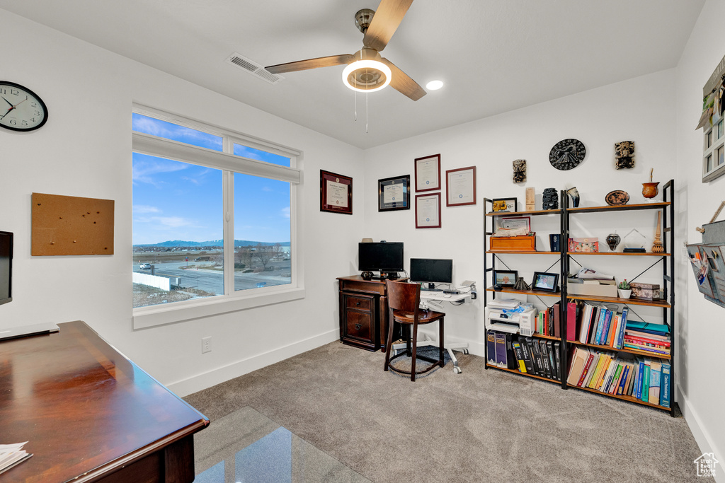 Office area featuring dark colored carpet, a water view, and ceiling fan