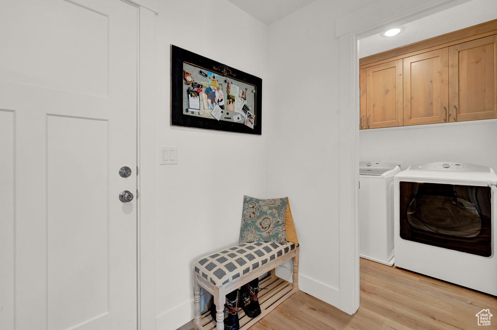 Laundry area with cabinets, washing machine and dryer, and light hardwood / wood-style floors