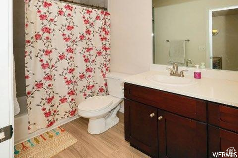 Full bathroom with hardwood / wood-style flooring, toilet, shower / bath combo, and oversized vanity