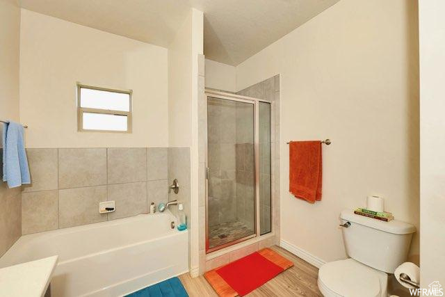 Full bathroom featuring wood-type flooring, independent shower and bath, vanity, and toilet