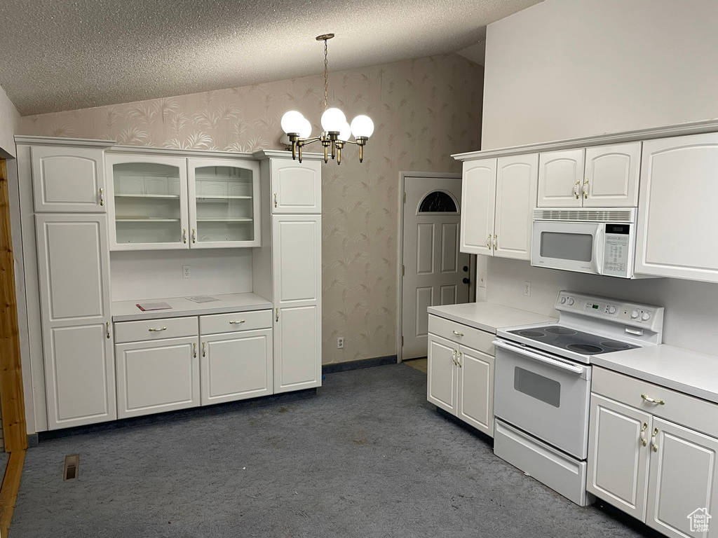 Kitchen with white cabinetry, a chandelier, dark carpet, white appliances, and vaulted ceiling